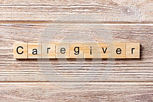 Caregiver word written on wood block. Caregiver text on table, concept photo