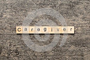Caregiver word written on wood block. Caregiver text on table, concept photo