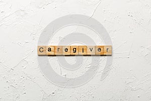 Caregiver word written on wood block. Caregiver text on table, concept photo