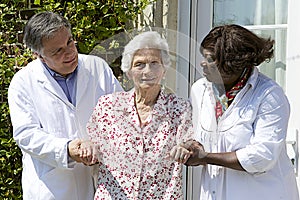 Caregivers assisting a senior patient walking outside