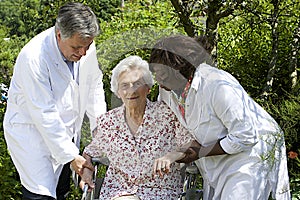 Caregivers assisting a senior patient in wheelchair