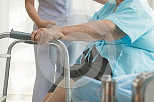 Caregivers help elderly to walk in the physical therapy.