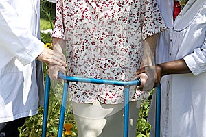 Caregivers helping a senior patient with her walker outdoor photo