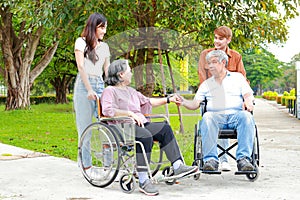 caregivers take elderly people in wheelchairs to breathe fresh air at an outdoor garden