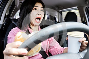 careless Asian woman's car accident with food and drink in hand on steering wheel