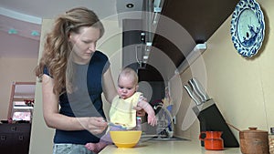Careless babysitter woman feed baby on table in kitchen. 4K