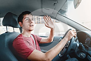 Careless car driver raises his hand in thanks for giving way. Traffic rules and politeness concept