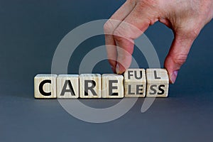 Careless or careful concept. Male hand flips wooden cubes and changes the word `careless` to `careful`. Beautiful grey backgro