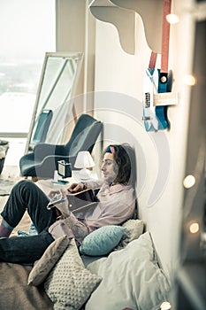 Careless dark-haired man in colorful bandana and stylish outfit