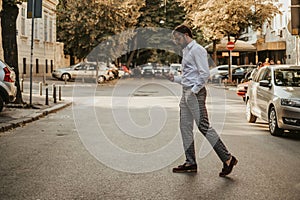 Careless man looking at mobile phone while crossing the street