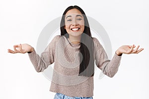 Careless and unbothered laughing happy asian woman with dark hair, shrugging and spread hands sideways uninvolved