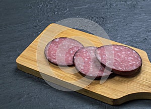 Carelessly chopped slices of smoked sausage on a wooden cutting board