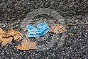 Carelessly discarded blue face mask on a sidewalk during the corona pandemic,