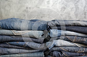 Carelessly folded jeans in two piles on a gray background. Close-up of jeans in different colors. Copy space