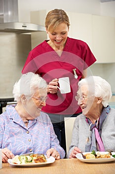 Carer drinking tea with two elderly woman