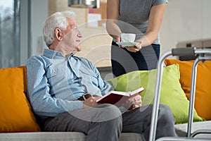 Carer giving disabled man coffee