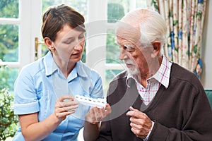 Carer Helping Senior Man With Medication