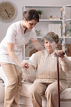 Carer helping senior with stick