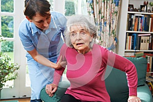 Carer Helping Senior Woman Out Of Chair