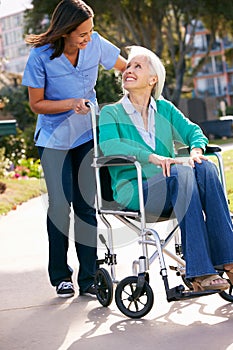 Carer Pushing Senior Woman In Wheelchair