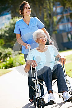 Carer Pushing Senior Woman In Wheelchair