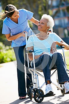 Carer Pushing Senior Woman In Wheelchair