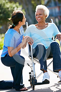 Carer Pushing Senior Woman In Wheelchair