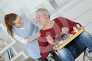 Carer serving meal to man in wheelchair at home