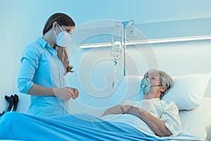 Carer wearing a surgical mask checking on patient