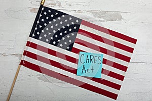 CARES ACT on blue posted note sitting on large American flag