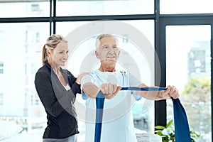 She really cares about her patients. a a physiotherapist working with a senior patient using a resistance band.