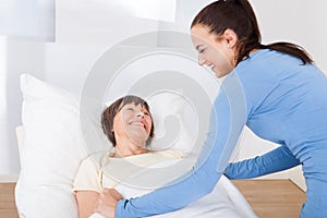 Caretaker covering senior woman with blanket photo