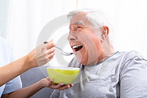 Caretaker Feeding Senior Man