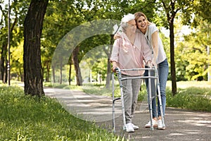 Caretaker helping elderly woman with walking frame photo