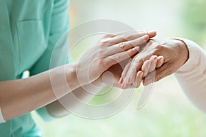 Caretaker massaging pensioner`s hand
