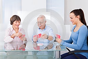 Caretaker playing cards with senior couple photo