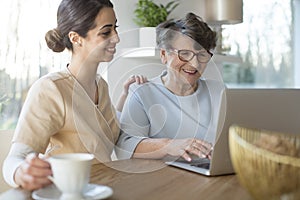 Caretaker and senior with laptop