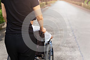 Caretaker spending time outdoor with patient in wheelchair.