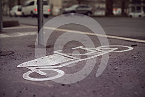 A cargo bike symbol is painted on the tarmac of a bicycle parking space in front of an urban grocery store.