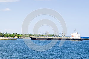 Cargo boat arriving at the entrance of the port of Santo Domingo, Dominican Republic with a tropical blue sea