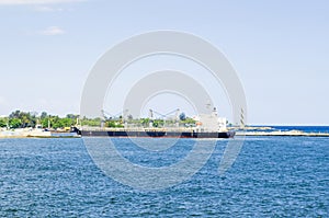 Cargo boat arriving at the entrance of the port of Santo Domingo, Dominican Republic with a tropical blue sea