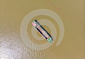 Cargo boat floating on the Mekong River Delta region, Can Tho, South Vietnam. Directly above top down nautical vessel on brown