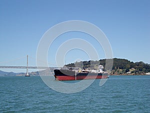 Cargo Boat in front of San Francisco Bay Bridge and Island