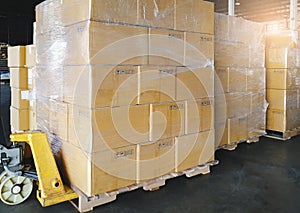 Cargo boxes shipment, Manufacturing and warehousing. Stack of cardboard boxes on pallet and hand pallet truck at the warehouse.