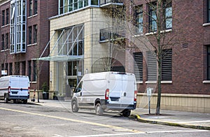 Cargo commercial mini vans standing on the urban city street with multilevel buildings