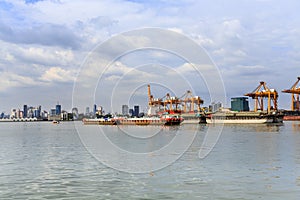 Cargo container ship being towed by the tug of cruising through the city