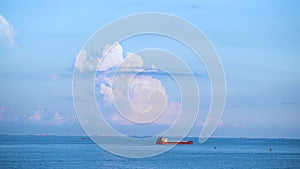 Cargo container ship sailing in still frozen summer sea on blue cloudy sky background. Shot. Red barge floating in blue