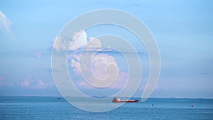 Cargo container ship sailing in still frozen summer sea on blue cloudy sky background. Shot. Red barge floating in blue