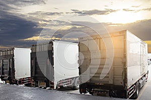 Cargo container truck parking at sunset sky at the warehouse. Road freight cargo shipment. Logistics and transportation.