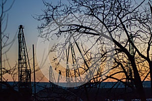 Cargo cranes silhouettes against dramatic blue and orange sunset sky, Varna, Bulgaria, crane in the port